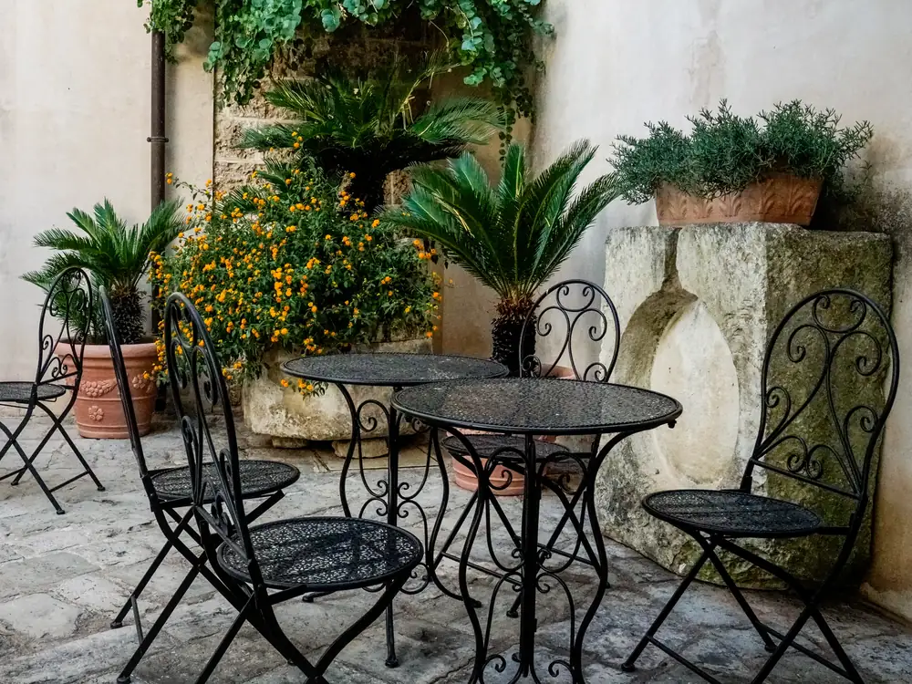 Tavolini in ferro battuto nella corte, tra le piante in vaso
