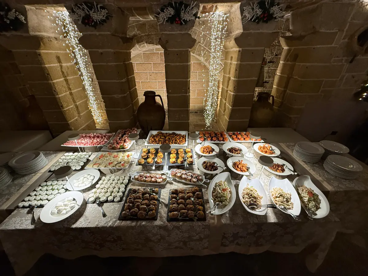 Il buffet degli antipasti sul tavolo in pietra, tra le anfore e le cascate di luci
