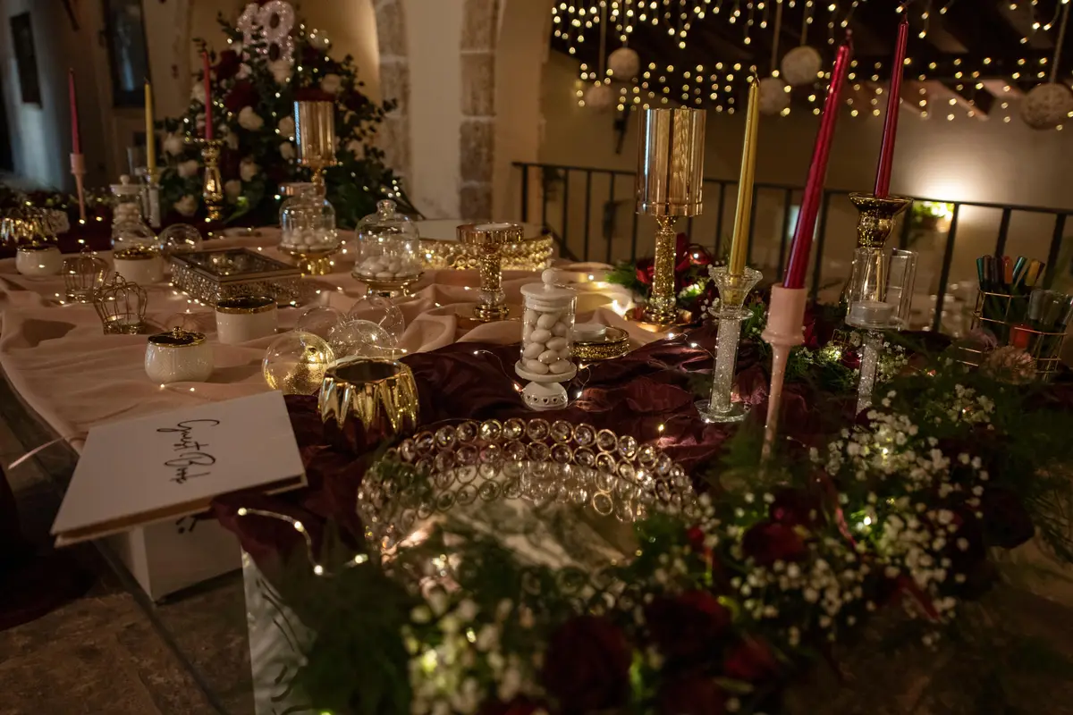 Dettaglio della tavola apparecchiata con candele, cristalli e verde