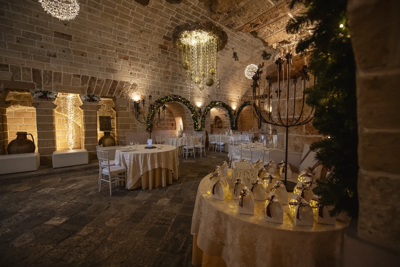 Il tavolo delle bomboniere col tovagliato in pizzo, accanto all&rsquo;arco