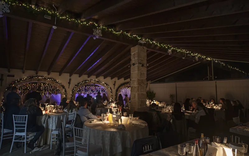 Gli ospiti a tavola durante una festa, tra le luci della sala degli archi
