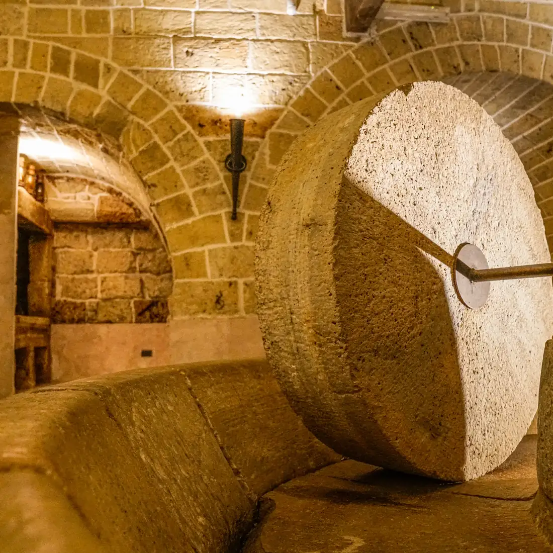 L'antica macina in pietra del frantoio sotto la volta